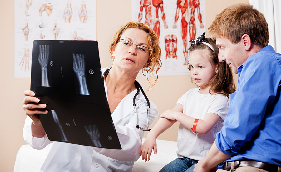 Doctor discusses x-ray with father and little girl.
